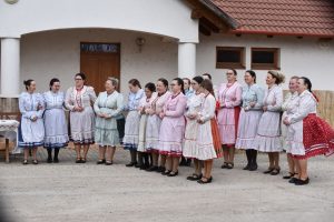 Women in colorful traditional folk dresses gather outdoors, showcasing cultural attire and community celebration.