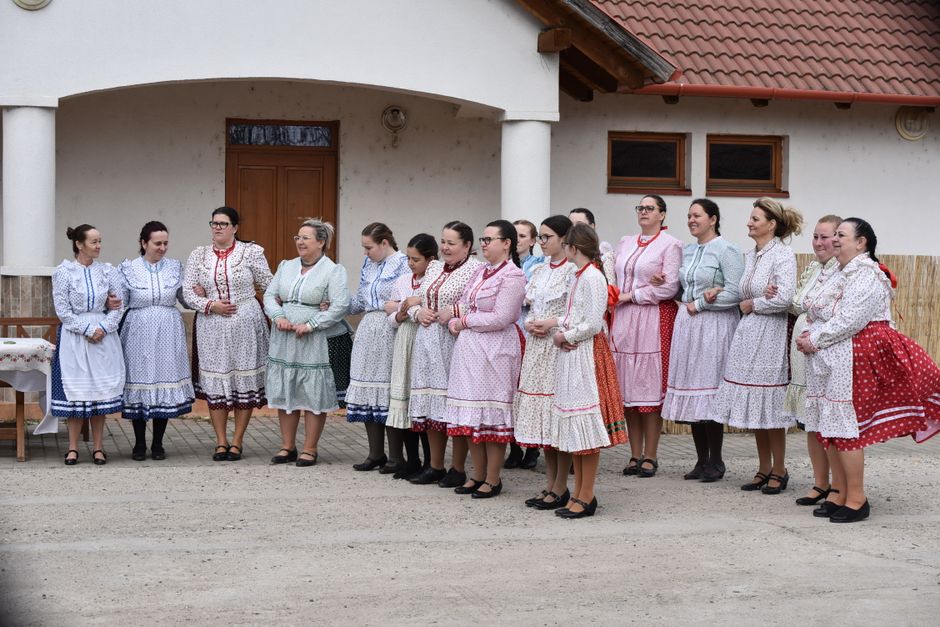 Women in colorful traditional folk dresses gather outdoors, showcasing cultural attire and community celebration.